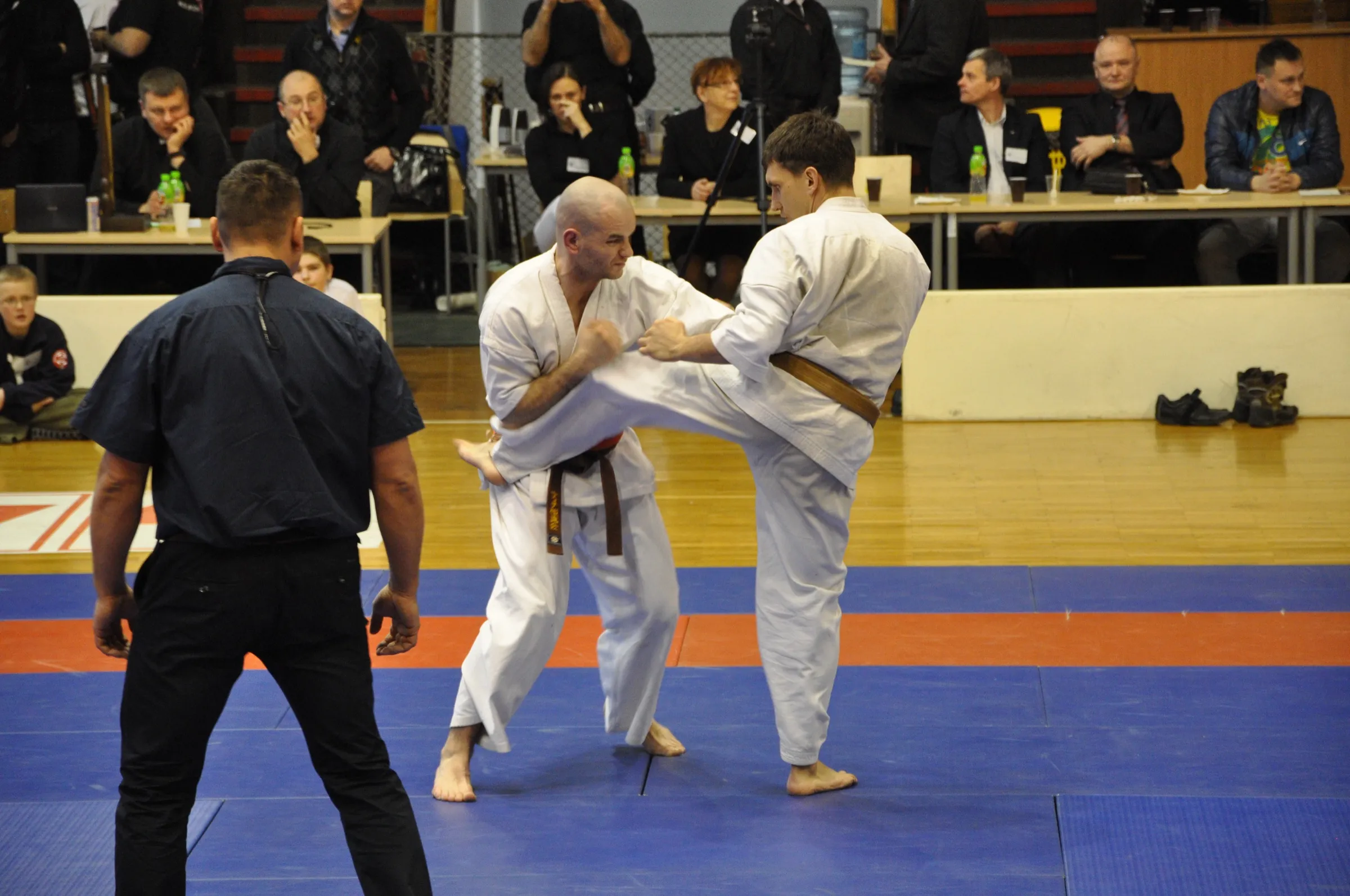 Walka kumite podczas turnieju karate kyokushin w Zabrzu w 2013 roku — zawodnik blokuje wysokie kopnięcie, sędzia prowadzi walkę