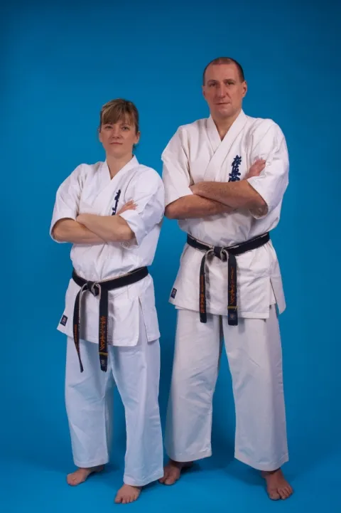 Sensei Beata i Piotr Machulec z założonymi rękami w karategi, niebieskie tło